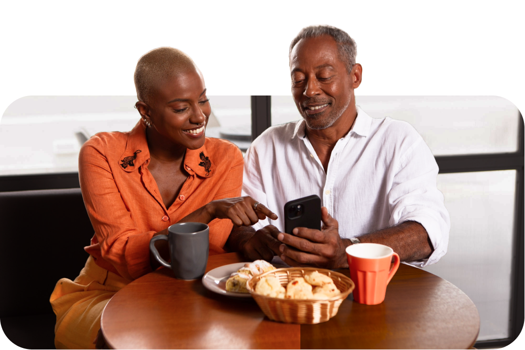 Imagem de duas pessoas felizes olhando para o celular.