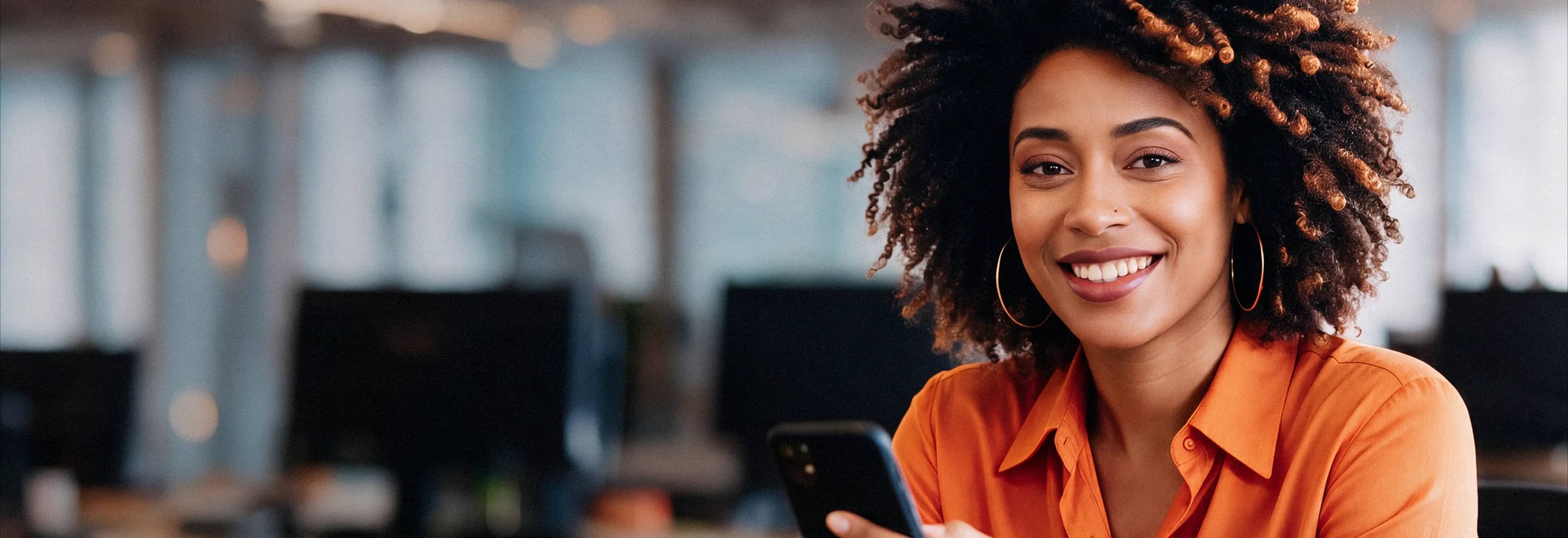 Mulher sorrindo segurando um celular.